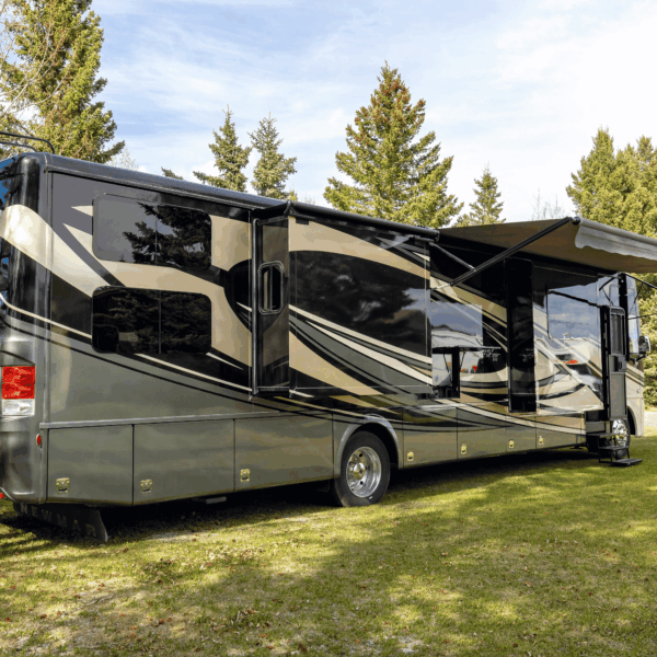 Luxury rv parked outside with grass and trees on a sunny day
