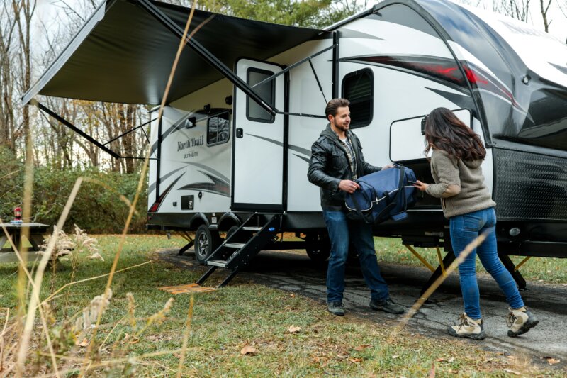 people loading item into an RV trailer that is parked outside